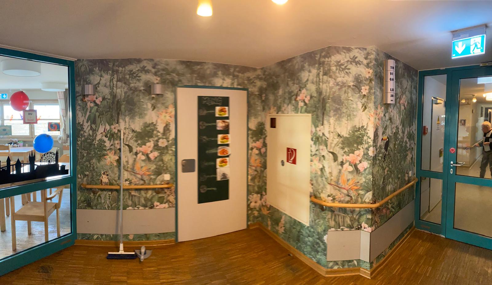 Ein Flur mit einer Tür und einer Wand, die mit dekorativem Tapetenmuster gestaltet ist.