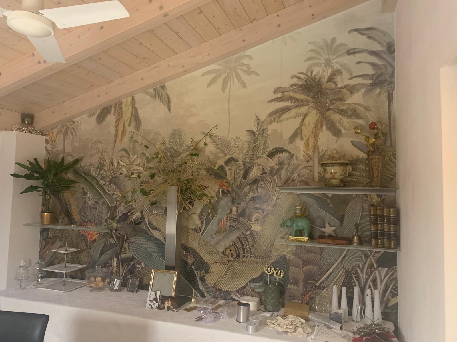 Wandmural mit tropischen Pflanzen und Palmen, das eine lebendige, exotische Atmosphäre schafft.