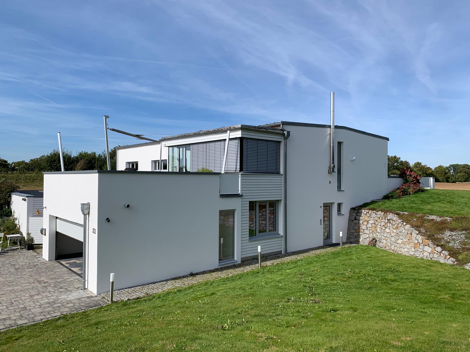 Modernes Haus mit großem, grünem Rasenbereich im Vordergrund.
